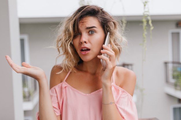 worried-curly-young-woman-pink-blouse-posing-during-phone-conversation-unhappy-caucasian-girl-with-blonde-hair-holding-smartphone-balcony_197531-9089